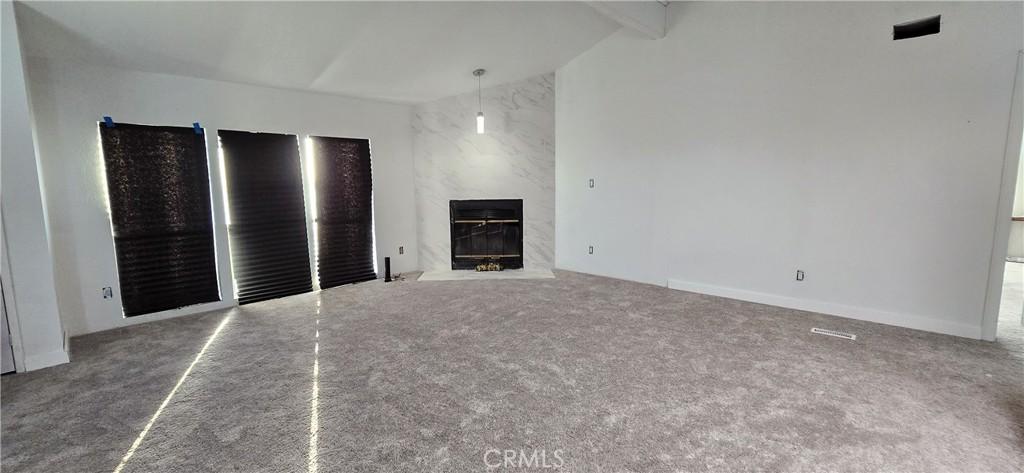 818 60th St W, Rosamond, CA 93560 - unfurnished living room with carpet floors and a premium fireplace