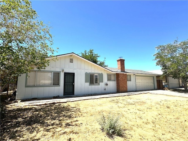 16069 Vine St, Hesperia, CA 92345 - ranch-style home featuring a garage, a chimney, board and batten siding, and driveway