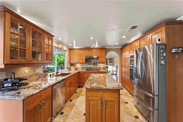 24236 Via, San Clemente, Mission Viejo, CA 92692 - kitchen featuring appliances with stainless steel finishes, arched walkways, recessed lighting, light stone countertops, and glass insert cabinets