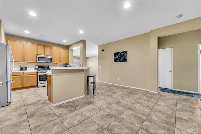 43627 Rialto Dr, Lancaster, CA 93535 - kitchen with appliances with stainless steel finishes, light countertops, a breakfast bar, recessed lighting, and light tile patterned floors
