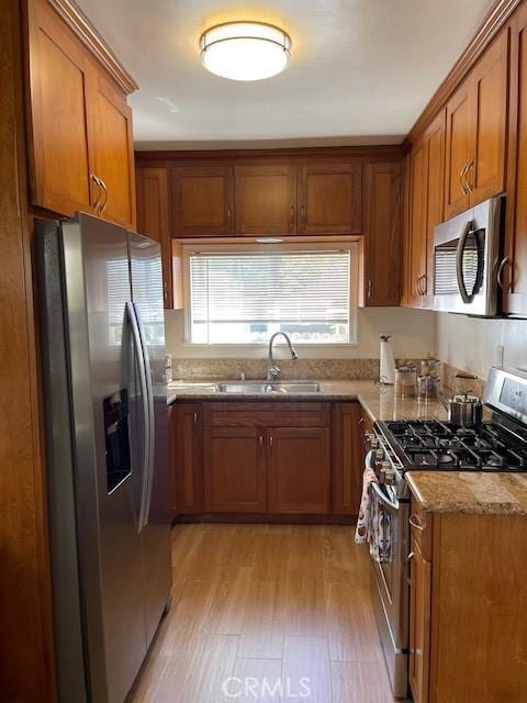 3257 Honolulu Ave, Glendale, CA 91214 - kitchen with appliances with stainless steel finishes, brown cabinets, light wood-style flooring, and light stone countertops