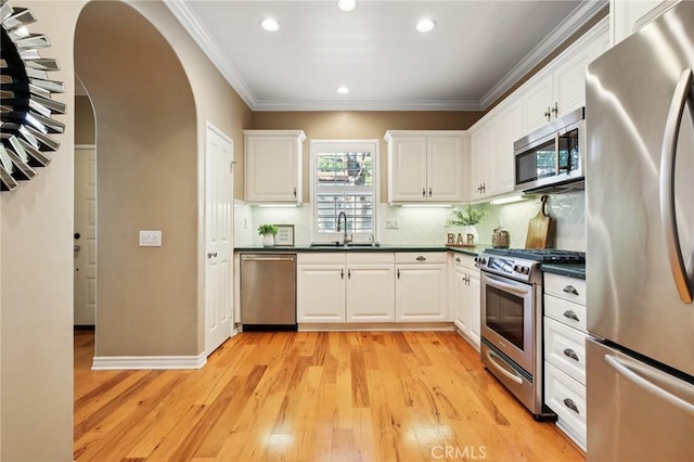 78 Windchime, Irvine, CA 92603 - kitchen featuring stainless steel appliances, dark countertops, light wood-style flooring, arched walkways, and recessed lighting