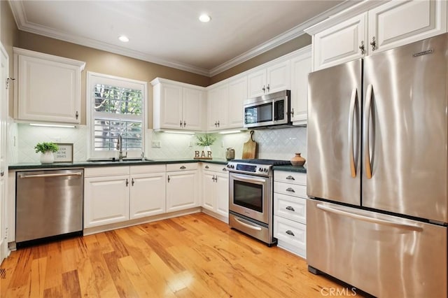 78 Windchime, Irvine, CA 92603 - kitchen with appliances with stainless steel finishes, dark countertops, crown molding, white cabinets, and light wood-style floors
