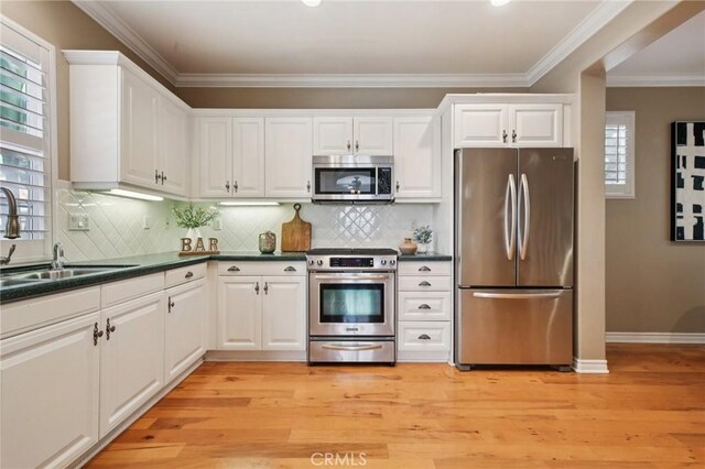 78 Windchime, Irvine, CA 92603 - kitchen featuring stainless steel appliances, dark countertops, light wood-style floors, white cabinets, and ornamental molding