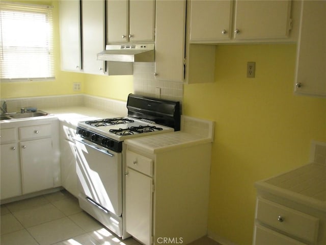 1237 S 3rd St, Alhambra, CA 91801 - kitchen featuring white range with gas cooktop, under cabinet range hood, backsplash, tile counters, and white cabinetry