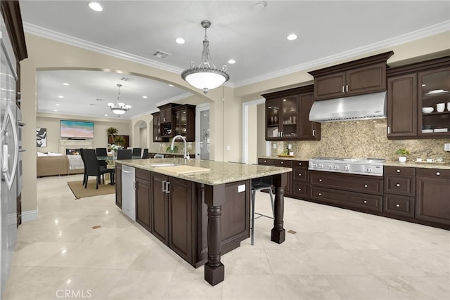 15841 Aurora Crest Dr, Whittier, CA 90605 - kitchen with under cabinet range hood, gas cooktop, arched walkways, a kitchen island with sink, and decorative backsplash