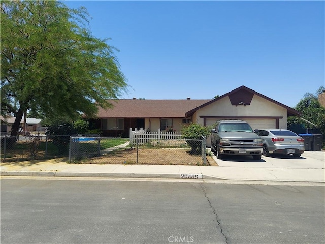 ranch-style home featuring an attached garage, driveway, and a fenced front yard