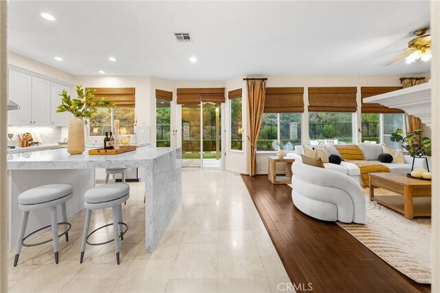 23665 Ridgecrest Ct, Diamond Bar, CA 91765 - kitchen with light stone countertops, white cabinets, recessed lighting, a ceiling fan, and a breakfast bar area
