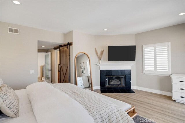 1722 Harper Ave, Redondo Beach, CA 90278 - bedroom featuring light wood-type flooring, recessed lighting, a barn door, and a tiled fireplace