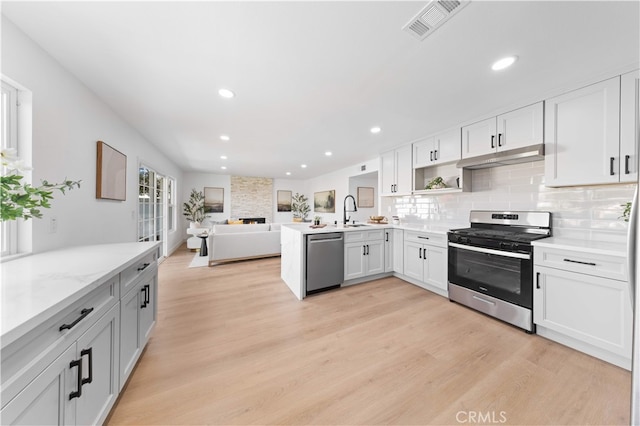 25885 Astor Way, Lake Forest, CA 92630 - kitchen featuring stainless steel appliances, a peninsula, open floor plan, light wood finished floors, and decorative backsplash