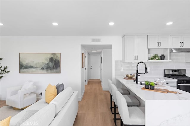 25885 Astor Way, Lake Forest, CA 92630 - kitchen with stainless steel gas range oven, open shelves, light wood finished floors, a breakfast bar, and recessed lighting