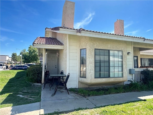 43731 8th St E, Lancaster, CA 93535 - property entrance with a chimney, a lawn, stucco siding, and a tiled roof