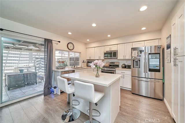 16011 Sugarpine Ln, Cerritos, CA 90703 - kitchen featuring stainless steel appliances, light wood finished floors, light countertops, a kitchen bar, and recessed lighting