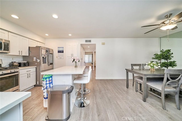 16011 Sugarpine Ln, Cerritos, CA 90703 - kitchen with appliances with stainless steel finishes, light wood-style floors, a kitchen breakfast bar, ceiling fan, and a kitchen island