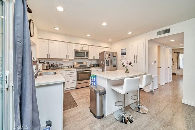16011 Sugarpine Ln, Cerritos, CA 90703 - kitchen with stainless steel appliances, a kitchen breakfast bar, light wood-style flooring, light countertops, and recessed lighting