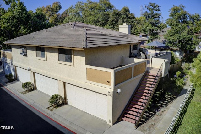 644 Orwell Ln, Ventura, CA 93003 - view of side of home with a garage, stucco siding, driveway, a chimney, and stairs