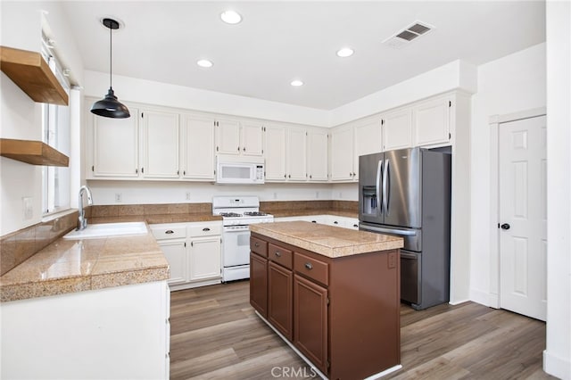 31257 Casera Ct, Menifee, CA 92584 - kitchen with white appliances, tile countertops, wood finished floors, white cabinets, and recessed lighting