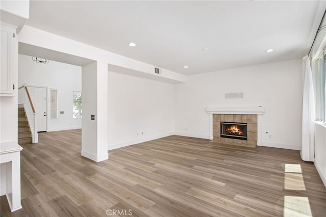 31257 Casera Ct, Menifee, CA 92584 - unfurnished living room with a tile fireplace, light wood-style floors, recessed lighting, and stairs