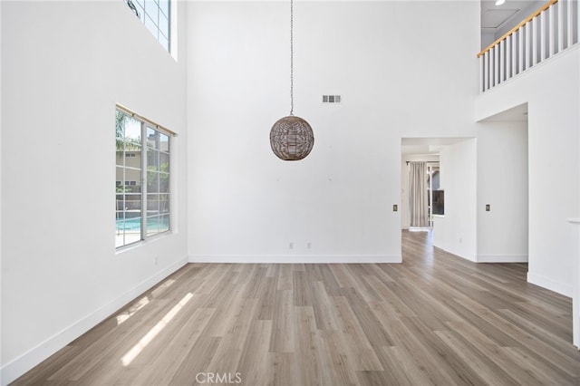 31257 Casera Ct, Menifee, CA 92584 - unfurnished living room featuring a towering ceiling, healthy amount of natural light, and wood finished floors