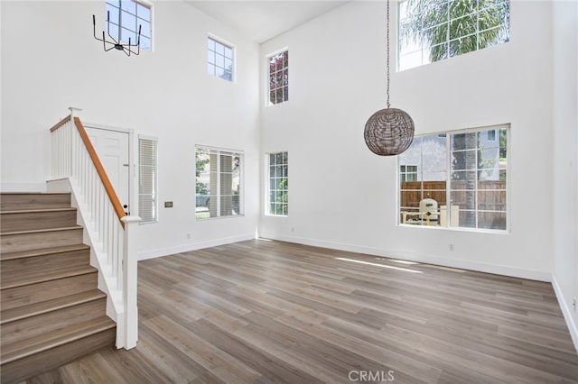 31257 Casera Ct, Menifee, CA 92584 - unfurnished living room with a chandelier, stairway, a towering ceiling, and wood finished floors