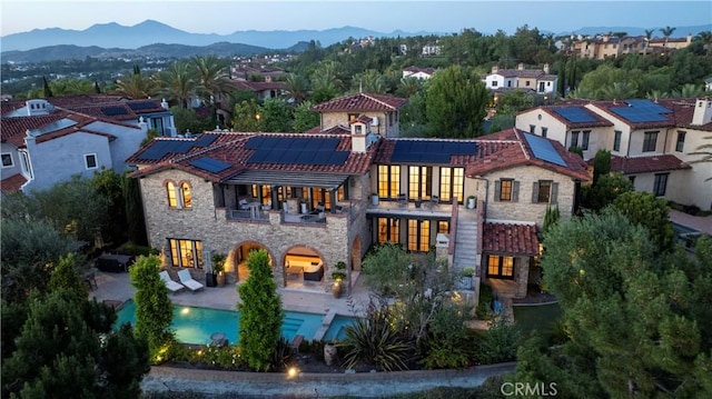 4 Thomas Rd, Ladera Ranch, CA 92694 - back of property with a balcony, stone siding, a tiled roof, an outdoor pool, and roof mounted solar panels