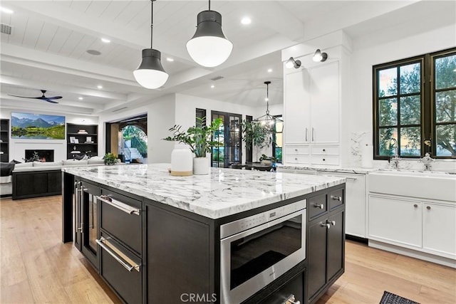 4 Thomas Rd, Ladera Ranch, CA 92694 - kitchen featuring stainless steel microwave, light wood finished floors, white cabinetry, ceiling fan, and open floor plan