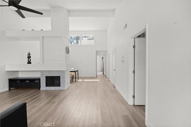 29 Morena Unit 35, Irvine, CA 92612 - unfurnished living room featuring a ceiling fan, light wood finished floors, a tiled fireplace, and lofted ceiling