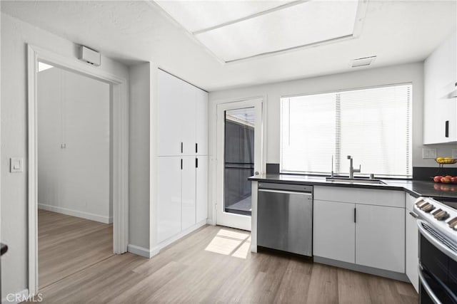 29 Morena Unit 35, Irvine, CA 92612 - kitchen with appliances with stainless steel finishes, dark countertops, light wood-style flooring, and white cabinetry