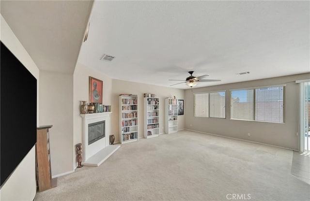 2354 Crimson Ave, Rosamond, CA 93560 - unfurnished living room featuring a glass covered fireplace, ceiling fan, and light carpet