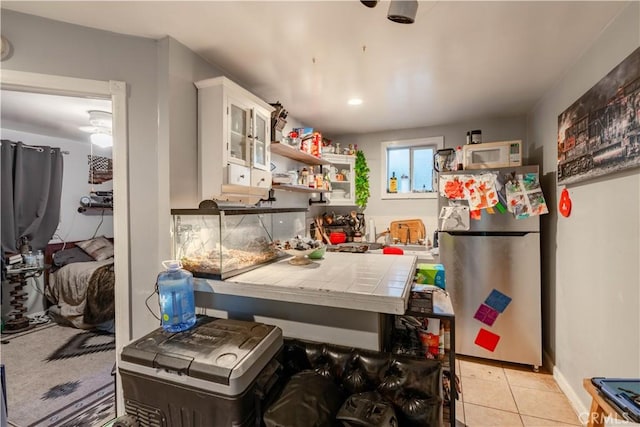7914 Magnolia Ave, Riverside, CA 92504 - kitchen featuring freestanding refrigerator, tile counters, white microwave, white cabinets, and light tile patterned flooring