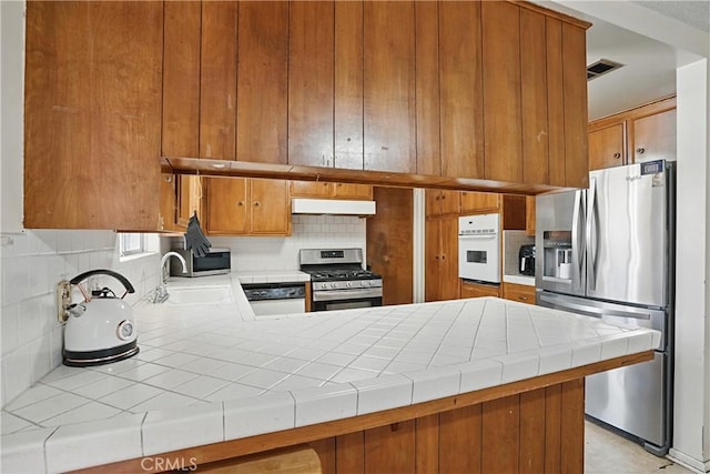 260 E Whittier Ave, Hemet, CA 92543 - kitchen featuring stainless steel appliances, under cabinet range hood, backsplash, and tile countertops