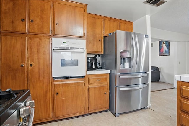 260 E Whittier Ave, Hemet, CA 92543 - kitchen with appliances with stainless steel finishes, tile countertops, and brown cabinets