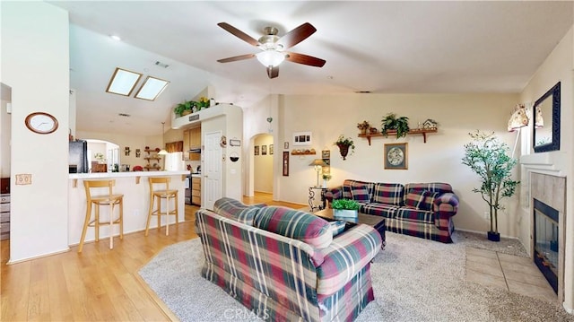 7075 Montana Ave, Fontana, CA 92336 - living room featuring a fireplace, a ceiling fan, vaulted ceiling, light wood finished floors, and arched walkways