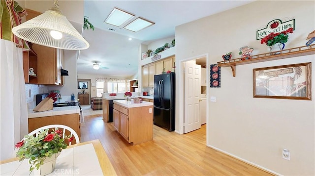 7075 Montana Ave, Fontana, CA 92336 - kitchen with freestanding refrigerator, light countertops, light wood-style floors, a kitchen island with sink, and lofted ceiling