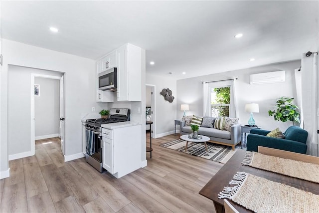 4400 Homer St, Los Angeles, CA 90031 - kitchen with stainless steel appliances, a wall mounted air conditioner, white cabinets, open floor plan, and light wood finished floors