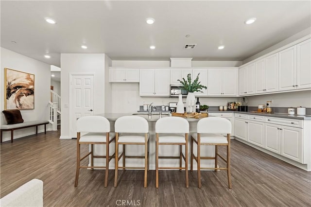 4733 S Rogers Way, Ontario, CA 91762 - kitchen featuring stainless steel microwave, dark wood-type flooring, white cabinets, a breakfast bar area, and recessed lighting