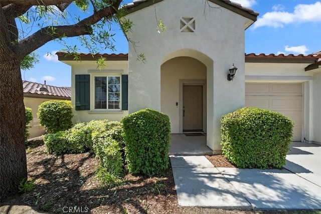 12744 Palmetto Ct, Riverside, CA 92503 - view of exterior entry with a tile roof, stucco siding, and an attached garage