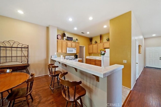 12744 Palmetto Ct, Riverside, CA 92503 - kitchen with white appliances, dark wood-style flooring, a breakfast bar area, a peninsula, and recessed lighting