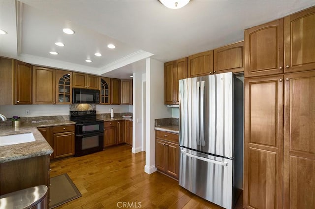 5185 Duenas, Laguna Woods, CA 92637 - kitchen featuring black appliances, brown cabinetry, dark wood-style floors, glass insert cabinets, and ornamental molding