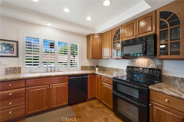 5185 Duenas, Laguna Woods, CA 92637 - kitchen with black appliances, crown molding, brown cabinetry, light wood-type flooring, and glass insert cabinets