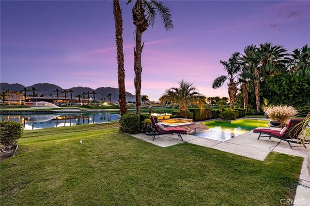 56102 Baltusrol Ln, Quinta, CA 92253 - yard at dusk featuring a lawn, a water and mountain view, and a patio