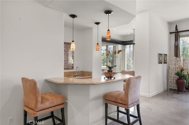 56102 Baltusrol Ln, Quinta, CA 92253 - kitchen with finished concrete floors, a breakfast bar, decorative light fixtures, a peninsula, and light stone counters