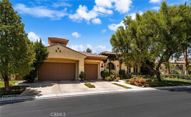 56102 Baltusrol Ln, Quinta, CA 92253 - mediterranean / spanish home featuring a garage, driveway, stucco siding, and a tiled roof