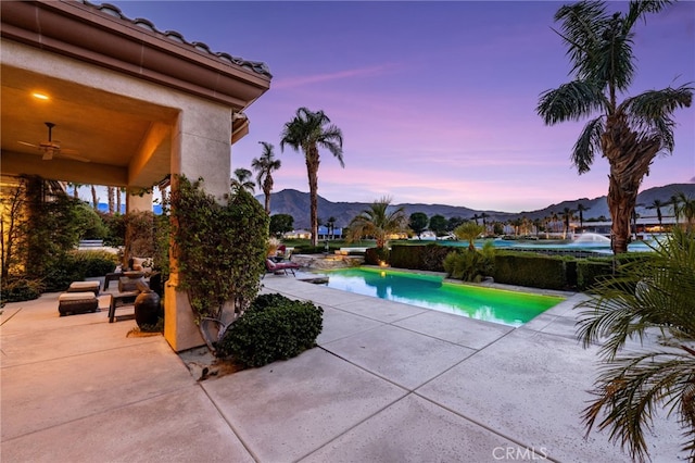 56102 Baltusrol Ln, Quinta, CA 92253 - pool at dusk featuring a patio, a mountain view, an outdoor pool, and a ceiling fan