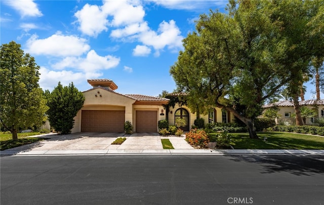 56102 Baltusrol Ln, Quinta, CA 92253 - mediterranean / spanish home with an attached garage, stucco siding, driveway, a tile roof, and a front lawn