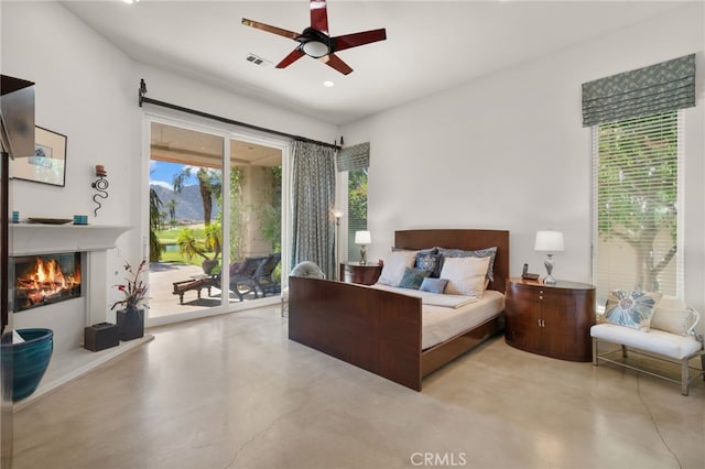 56102 Baltusrol Ln, Quinta, CA 92253 - bedroom with concrete flooring, access to outside, a warm lit fireplace, recessed lighting, and ceiling fan