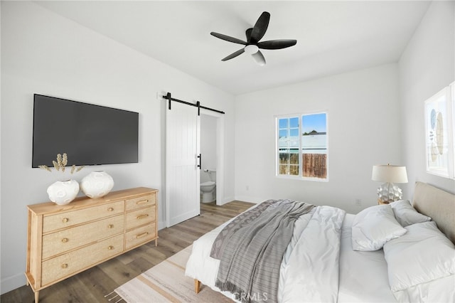 594 W 10th St, San Bernardino, CA 92410 - bedroom with a barn door, wood finished floors, connected bathroom, and a ceiling fan