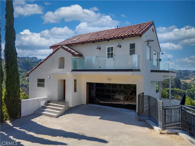 8280 Grand View Dr, Los Angeles, CA 90046 - view of front of house with stucco siding, driveway, a balcony, and a tile roof