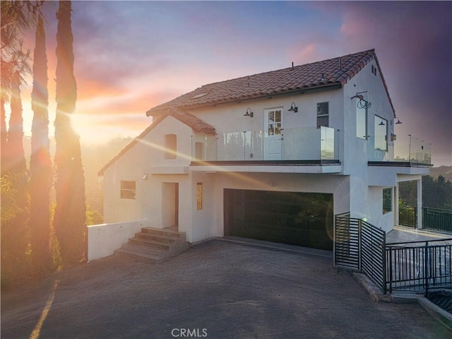 8280 Grand View Dr, Los Angeles, CA 90046 - back of house at dusk featuring a balcony, stucco siding, a tile roof, and driveway