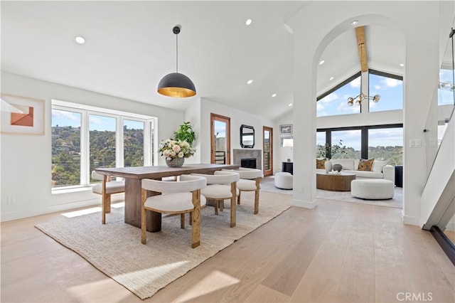 8280 Grand View Dr, Los Angeles, CA 90046 - dining room featuring beamed ceiling, a fireplace, light wood-style floors, high vaulted ceiling, and recessed lighting